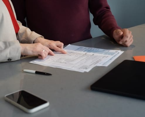 Bureau ou salle de conseil haut de gamme, lumière naturelle froide et maîtrisée, documents financiers ou structurels sobres en premier plan ou présents dans la scène. Atmosphère de réflexion stratégique confidentielle, pas d'action visible — plutôt la tension avant une décision structurante.